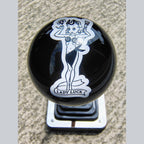 Front view of the Lady Luck resin shifter ball on a shifter — deep gloss black resin with vintage pinup girl artwork in white, holding a flower and wrench, with 'Lady Luck' banner below. Crystal-clear resin dome finish. 