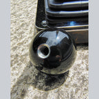 Underside of the Lady Luck resin shifter ball showing the stainless steel threaded insert for mounting on a shift lever. Deep gloss black resin body with chrome shift boot hardware visible in background.