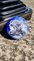The Bad Coupe Resin Shifter Ball in swirled blue and white resin, showing Von Franco's hand-drawn Yeti driving a blown chopped hot rod coupe beneath The Bad Coupe lettering, mounted beside a shifter boot