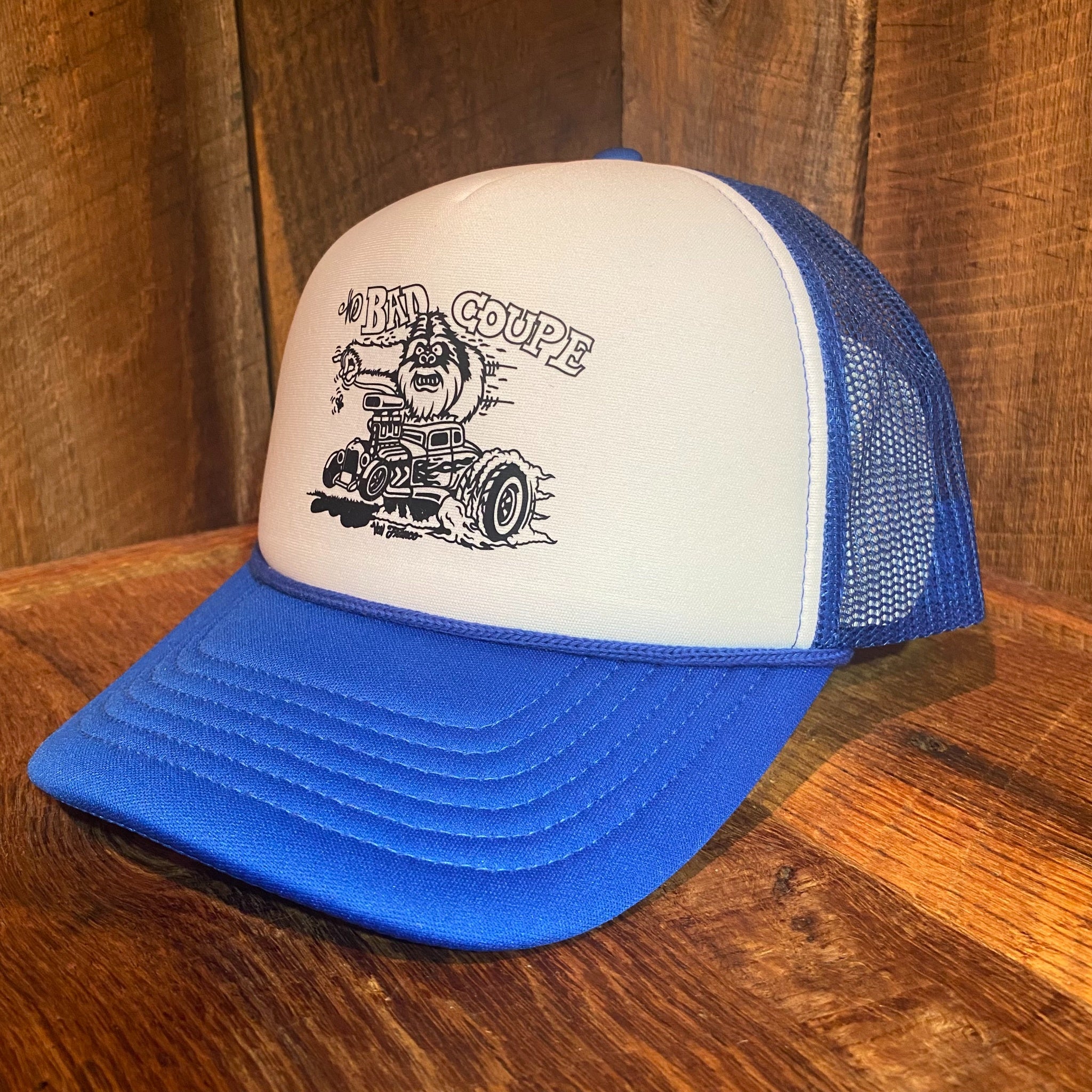 Right side view of The Bad Coupe Yeti Foam Trucker Hat in blue and white, showing the structured foam front panel and Von Franco artwork detail
