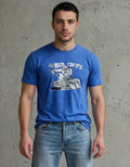 Man wearing a blue t-shirt with a graphic design against a concrete wall.